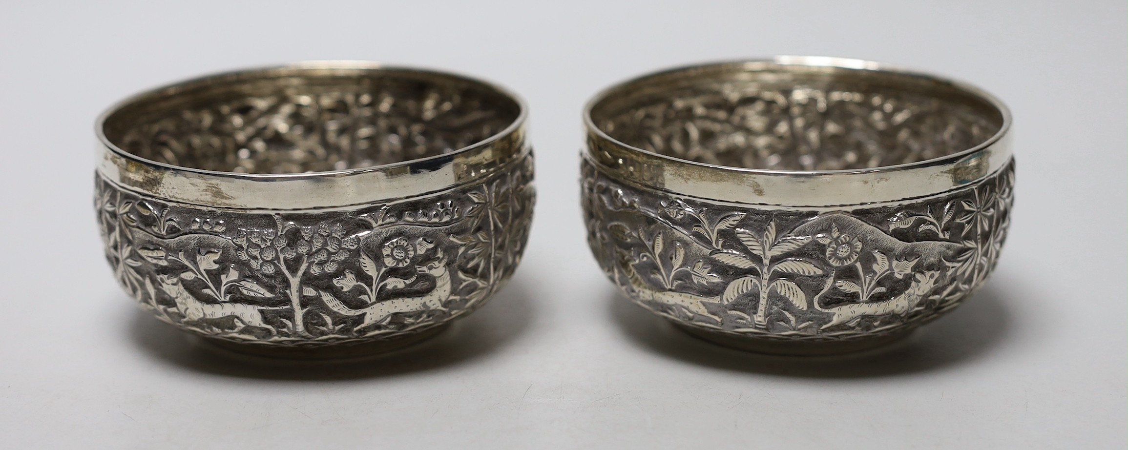 A pair of Indian embossed white metal finger bowls, diameter 97mm , a Persian white metal and turquoise set heart shaped paperweight and an Indian white metal and turquoise set heart shaped box.